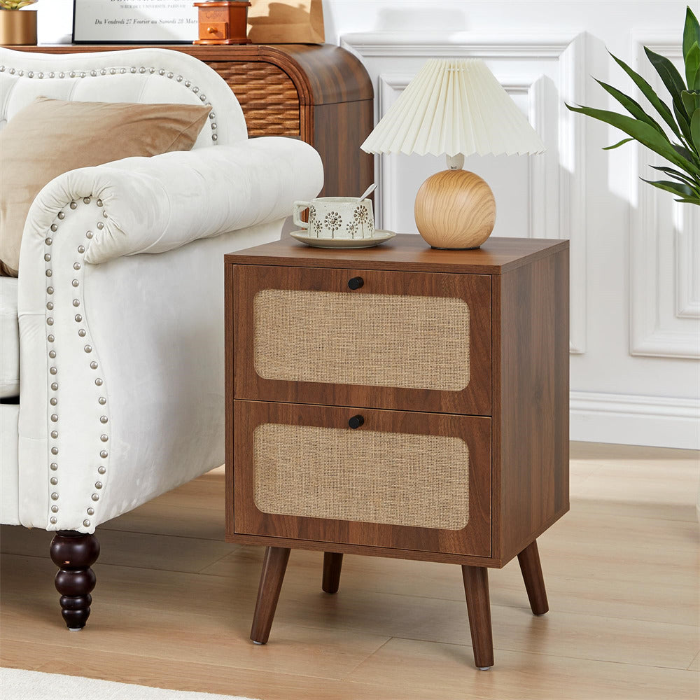 Wooden nightstand with two drawers next to a white armchair in a living room.