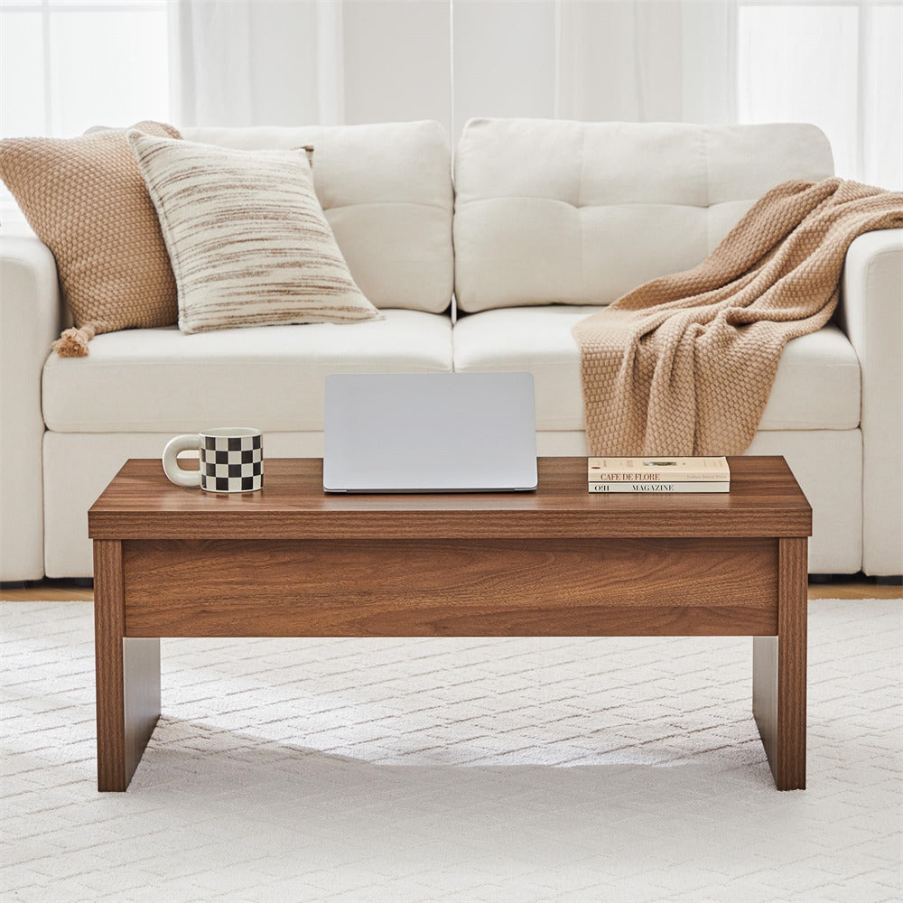 Wooden coffee table with a laptop, mug, and books in front of a beige sofa.