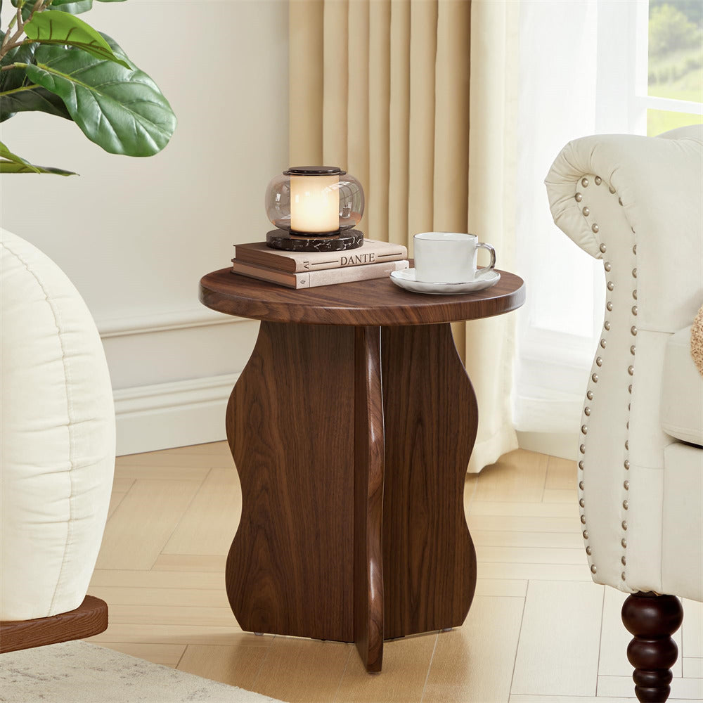 Wooden side table with a candle, books, and a cup in a living room setting.