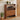 Wooden shoe cabinet with open door displaying shoes, next to a plant and a vase with flowers.