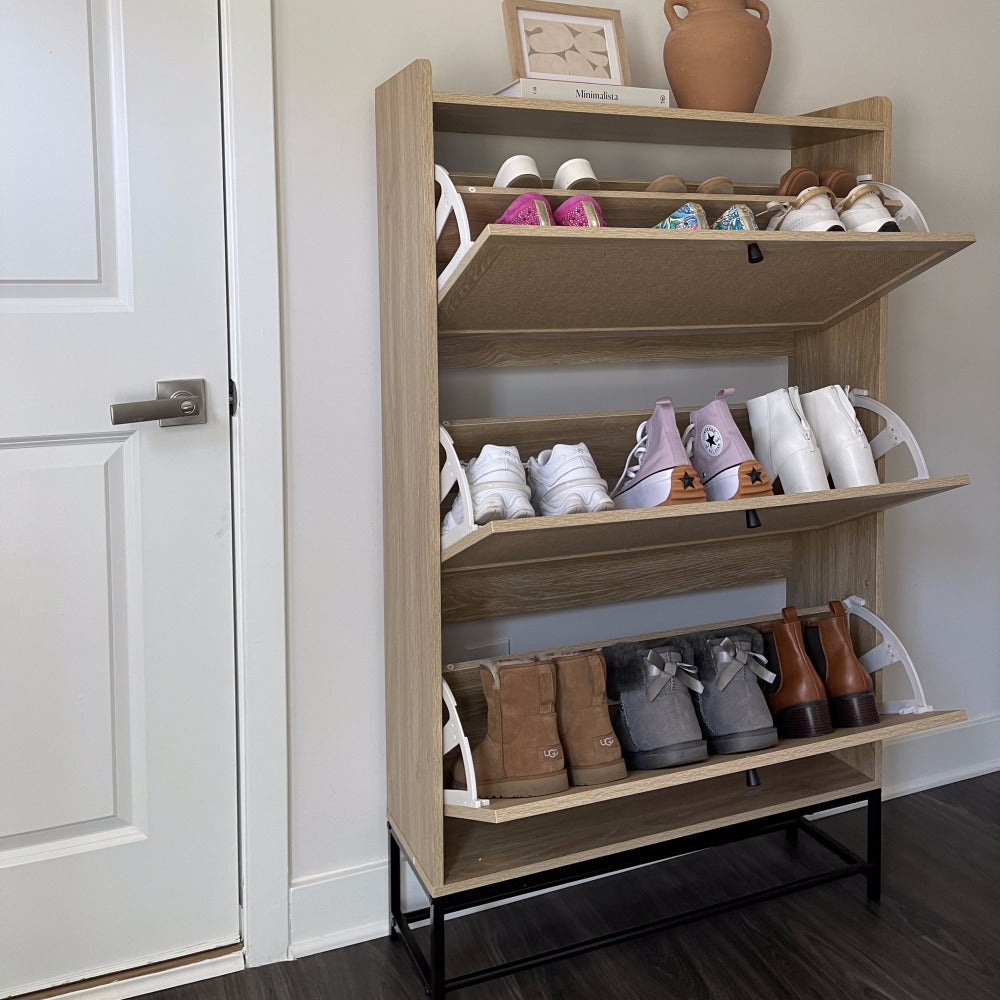 Wooden shoe rack with various shoes on shelves against a white wall.