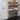 Wooden shoe rack with various shoes on shelves against a white wall.