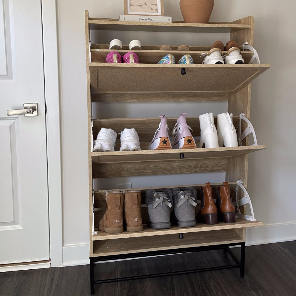 Wooden shoe rack with various shoes on shelves against a white wall.