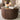 A round coffee table with a fluted vertical slat design and a medium brown wood top, styled in a living room setting with books, a candle, and a vase.