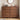 A pair of dark brown wooden 5-drawer chest dressers with rounded feet, styled in a bedroom setting with a round mirror, headphones, a radio, and toiletries on top.