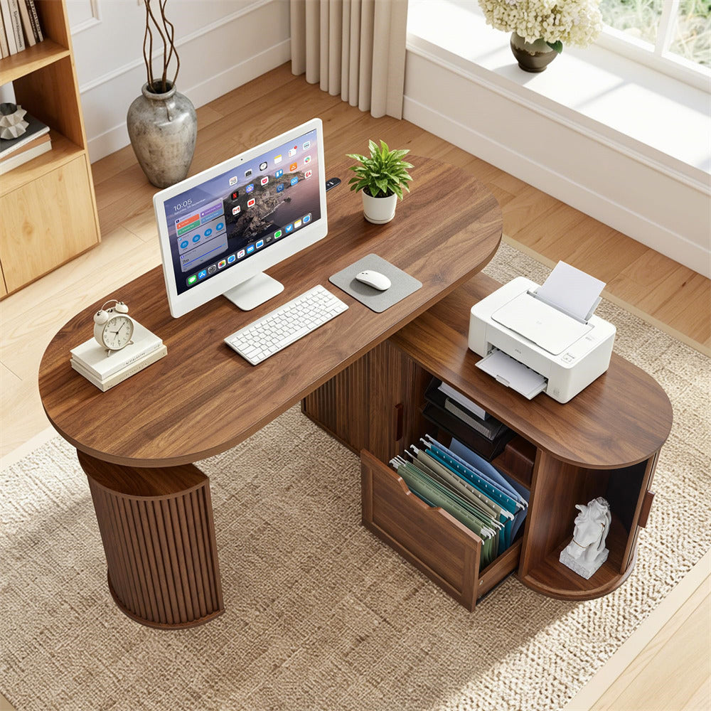 A modern walnut wood L-shaped desk with a curved top, featuring a computer monitor, keyboard, mouse, small plant, a white printer on the side table, open storage drawers, and a small shelf with a decorative bust, set in a bright home office environment.