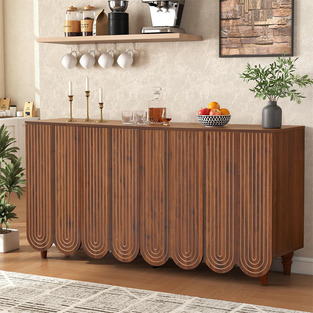 A wooden sideboard or credenza with a rich walnut finish, featuring a fluted vertical rib design and scalloped lower panels. The cabinet is styled in a modern kitchen setting with a wooden shelf, hanging mugs, a glass bottle, and decorative items on top.