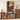 A tall wooden record and media shelf stands against a beige wall, holding vinyl records, CDs, and books. The room includes matching wood furniture, a speaker, a piano, and framed wall art.