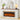 A white electric fireplace with a wood-look mantel and faux log flames, styled in a bright living room with a vase, framed art, books, and a table lamp.