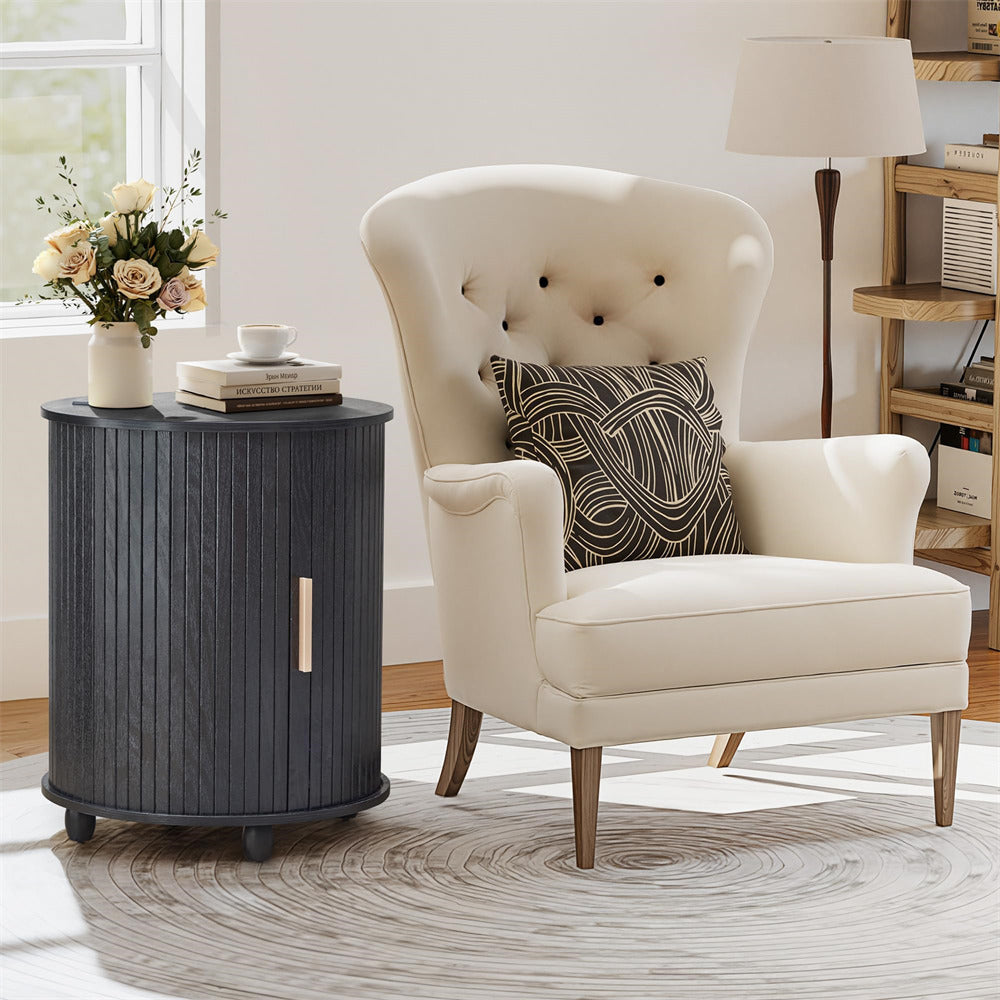 White armchair with a decorative pillow next to a dark wooden side table in a room with a lamp and window.