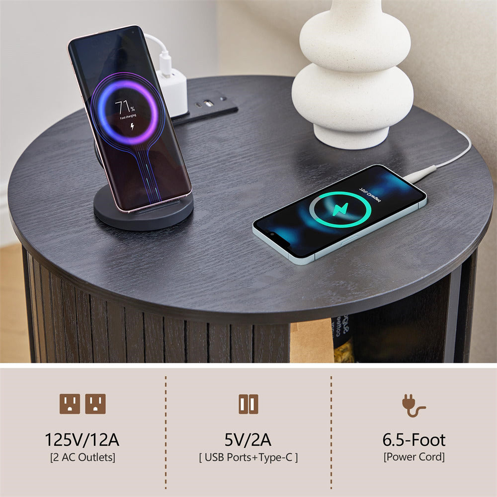 Two smartphones charging on a round wooden table with a decorative vase.