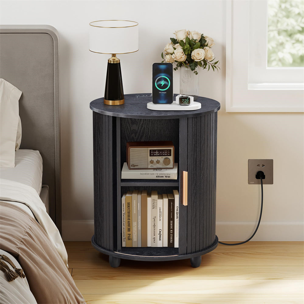 Round wooden nightstand with books, lamp, and decorative items in a bedroom setting.