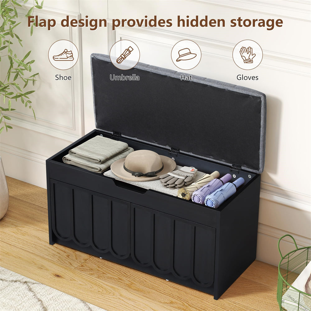 Black storage bench with open lid showing various items on a wooden floor.