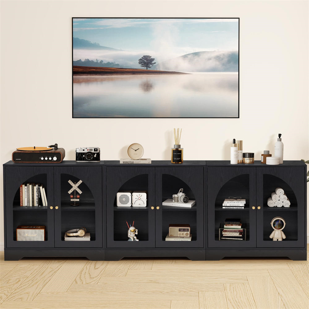 Black entertainment console with decorative items against a white wall with a mounted TV.