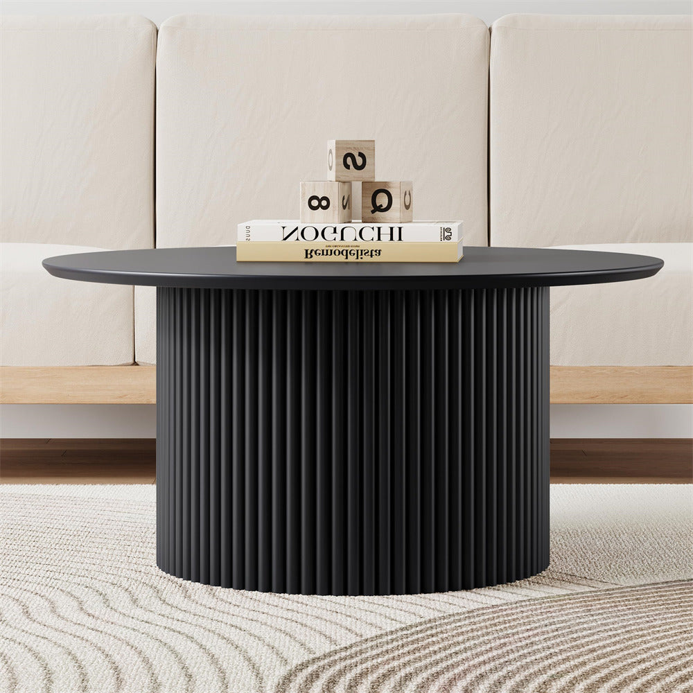 Black round coffee table with decorative items in a living room setting