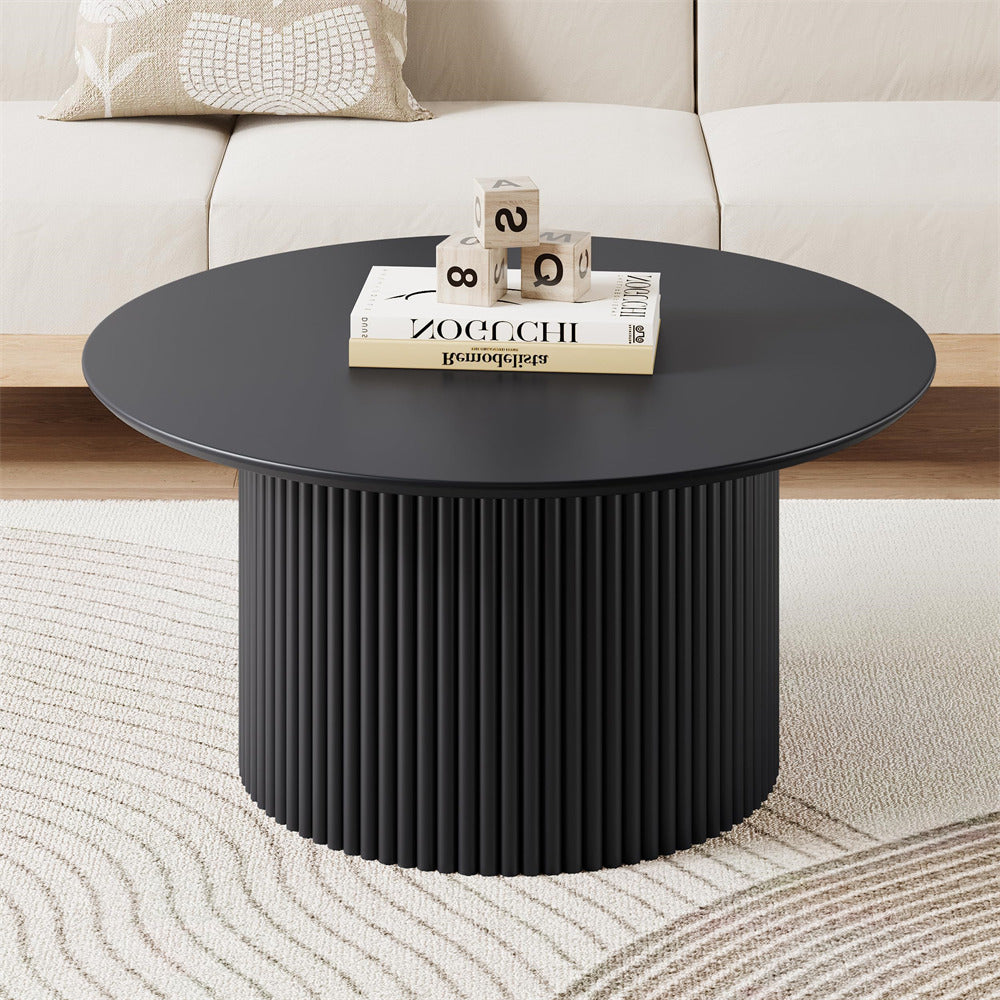 Black round coffee table with decorative items in a living room setting