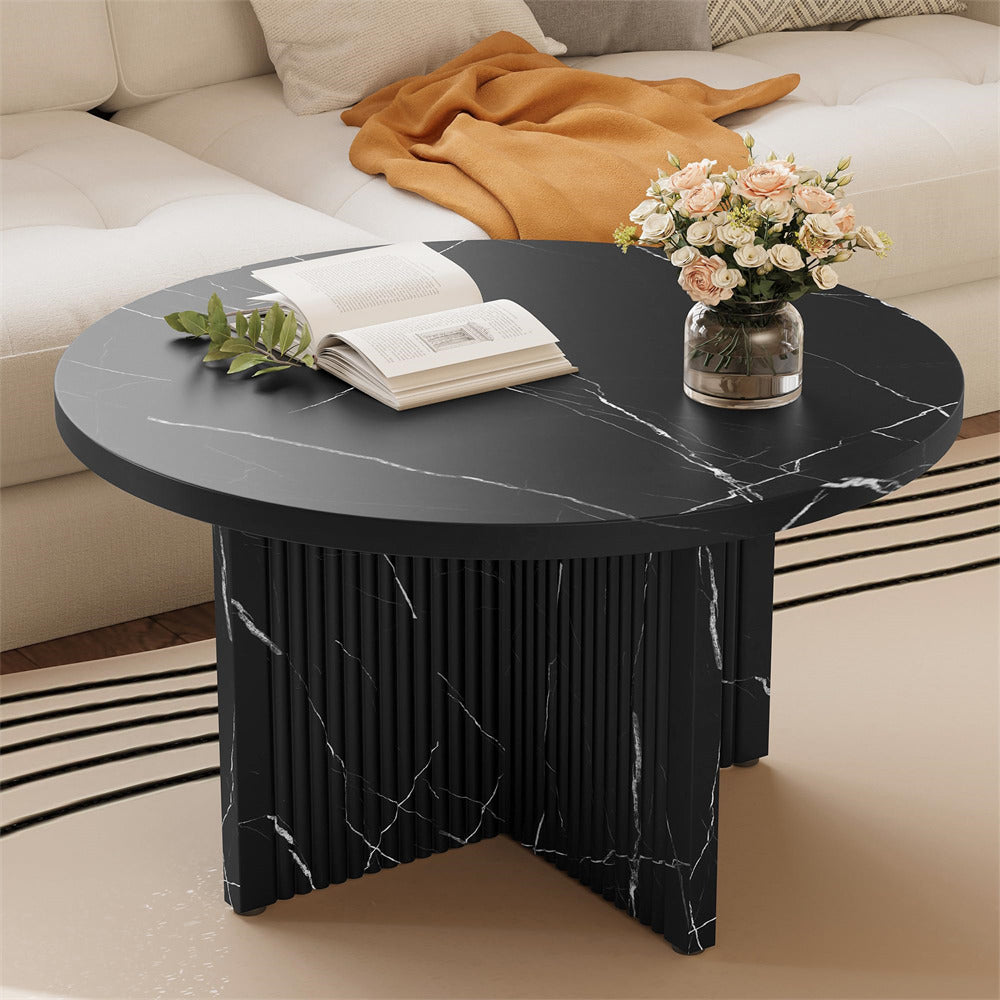 Black marble coffee table with a vase of flowers and an open book on a beige sofa background