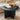Black marble coffee table with a vase of flowers and an open book on a beige sofa background