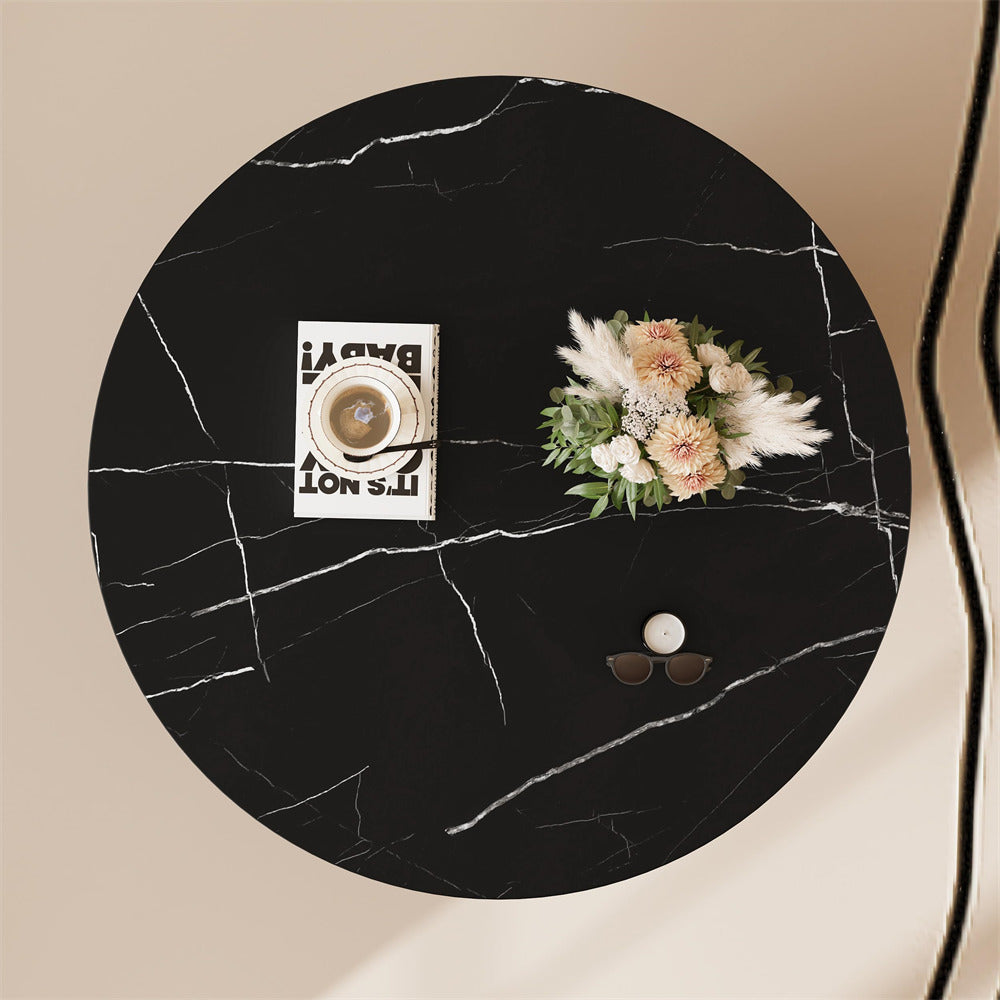 Round black marble table with decorative items on a beige background