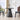 Modern black dining table with two chairs in a bright room with large windows.