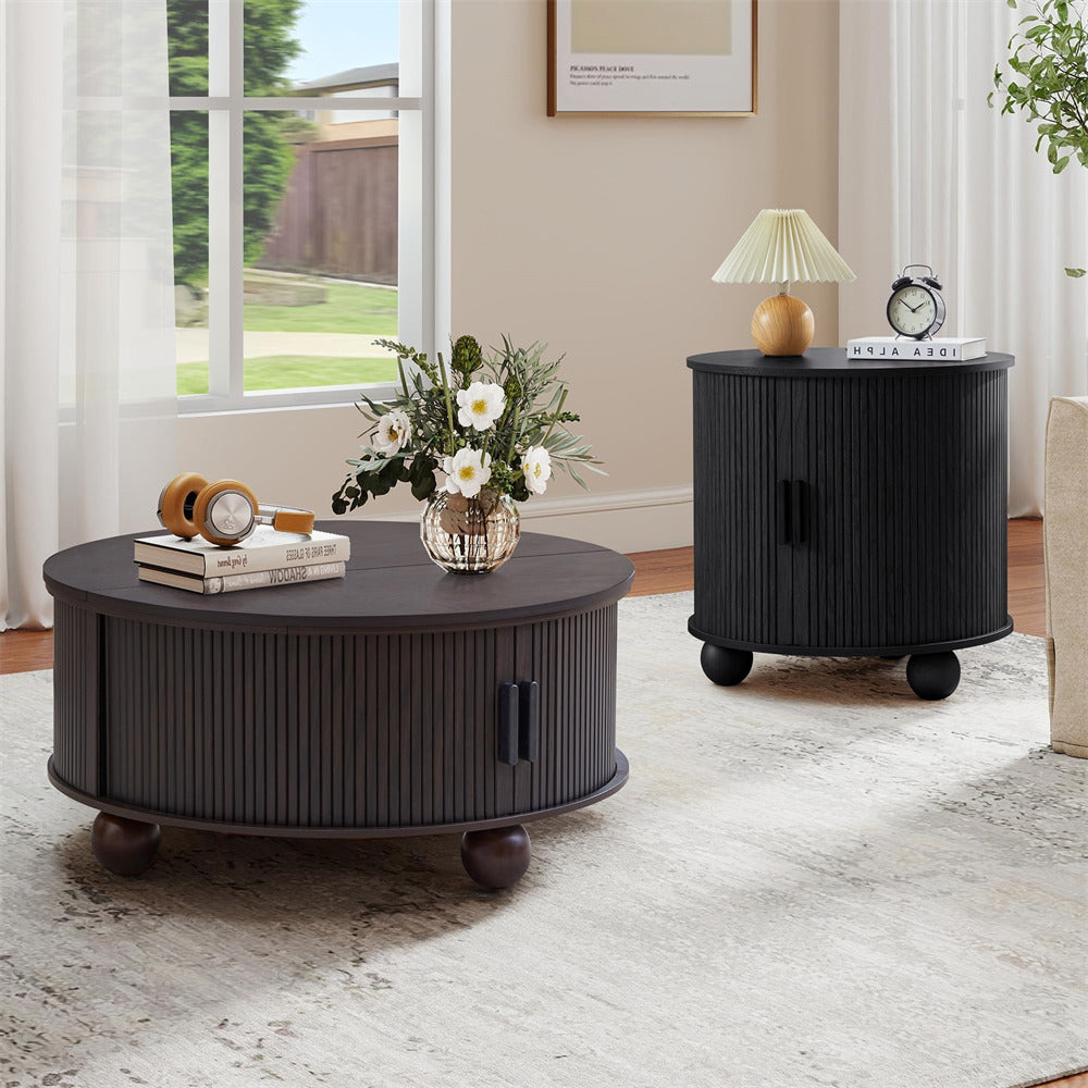 Round black coffee table with decorative items in a living room setting.