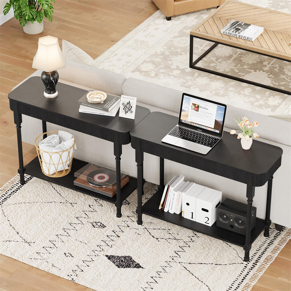 Black corner desk with laptop, books, and decor items in a living room setting.