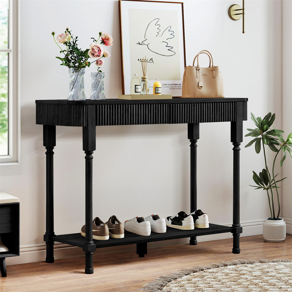 Black console table with shoes, plants, and decor items in a room.