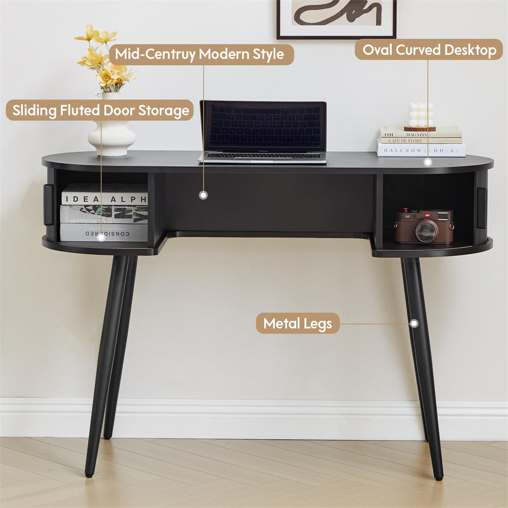 Black desk with oval curved desktop, sliding fluted door storage, and metal legs on a light wooden floor.