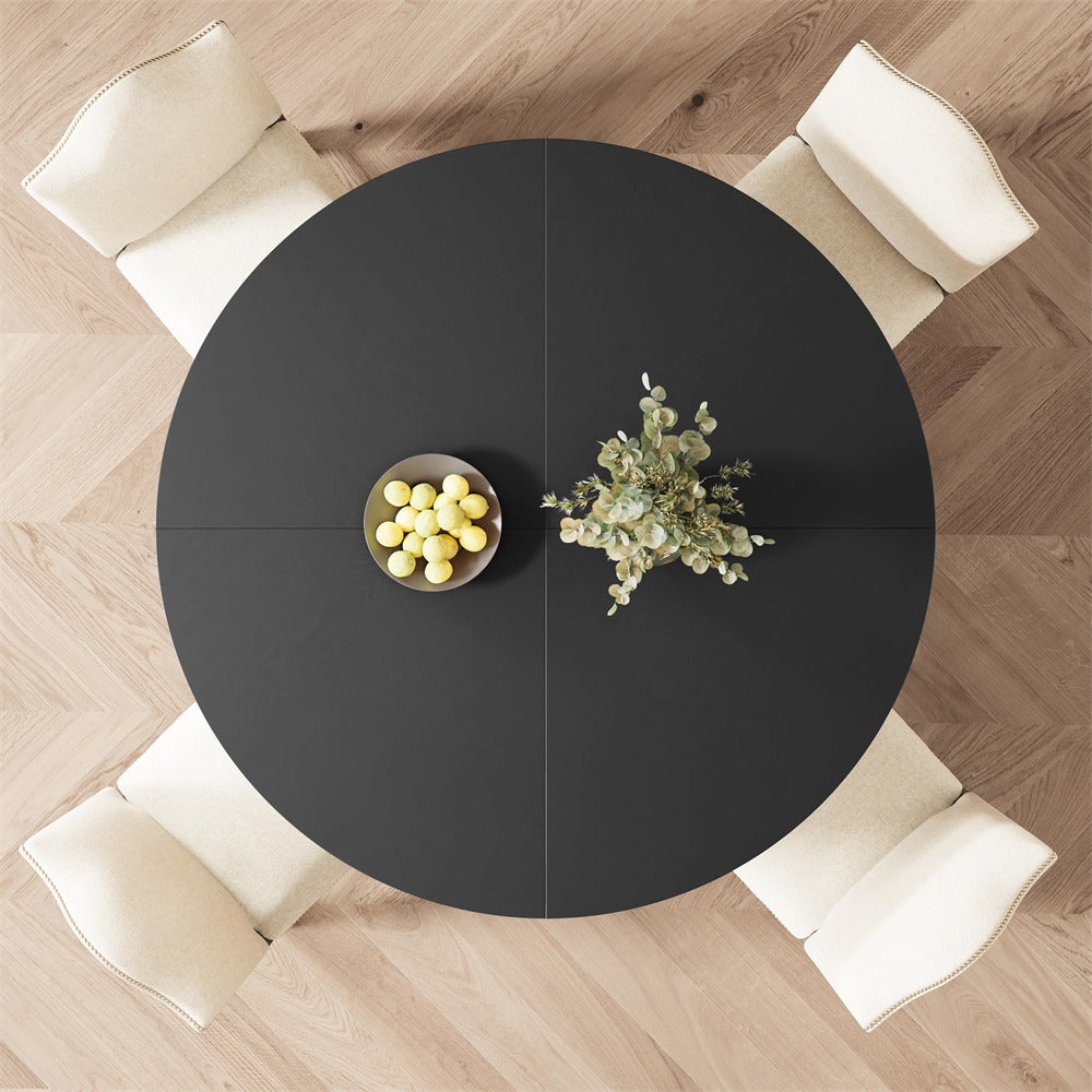 Round black dining table with decorative items in a room with wooden flooring and white chairs.