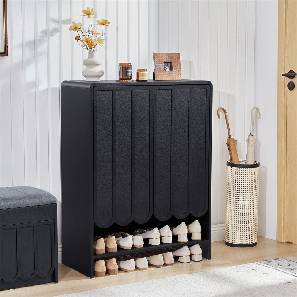 Black 5-tier wooden shoe cabinet with shoes inside, next to a white wall and wooden door.