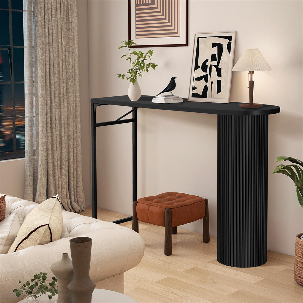 Modern living room with a black console table, ottoman, and decorative items.
