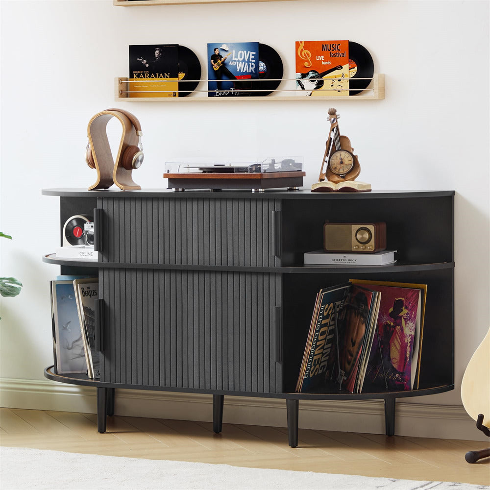 Black entertainment console with records and decor items against a white wall.