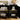 Black bookshelf with adjustable shelves, books, a teddy bear, and a radio on a wooden floor.