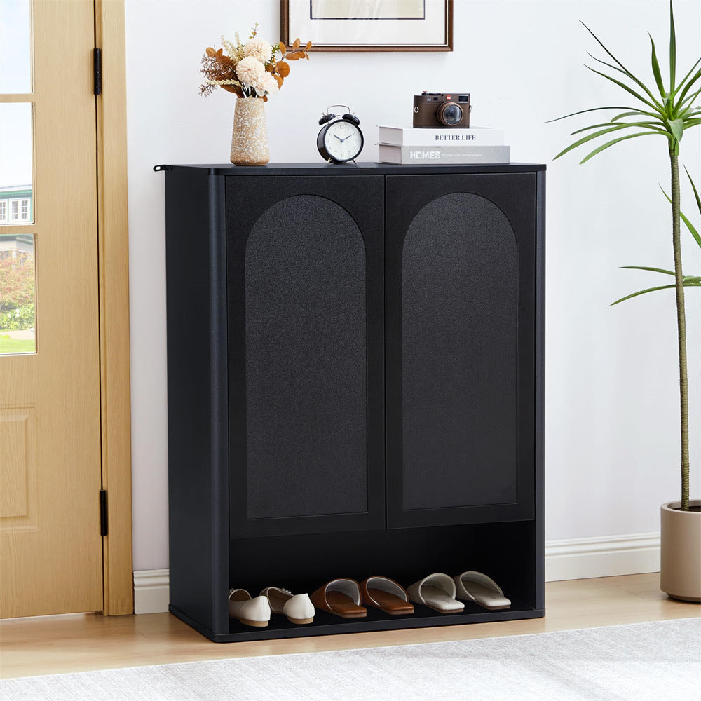 Black shoe cabinet with shoes inside, placed against a wall in a room with a plant and a clock.