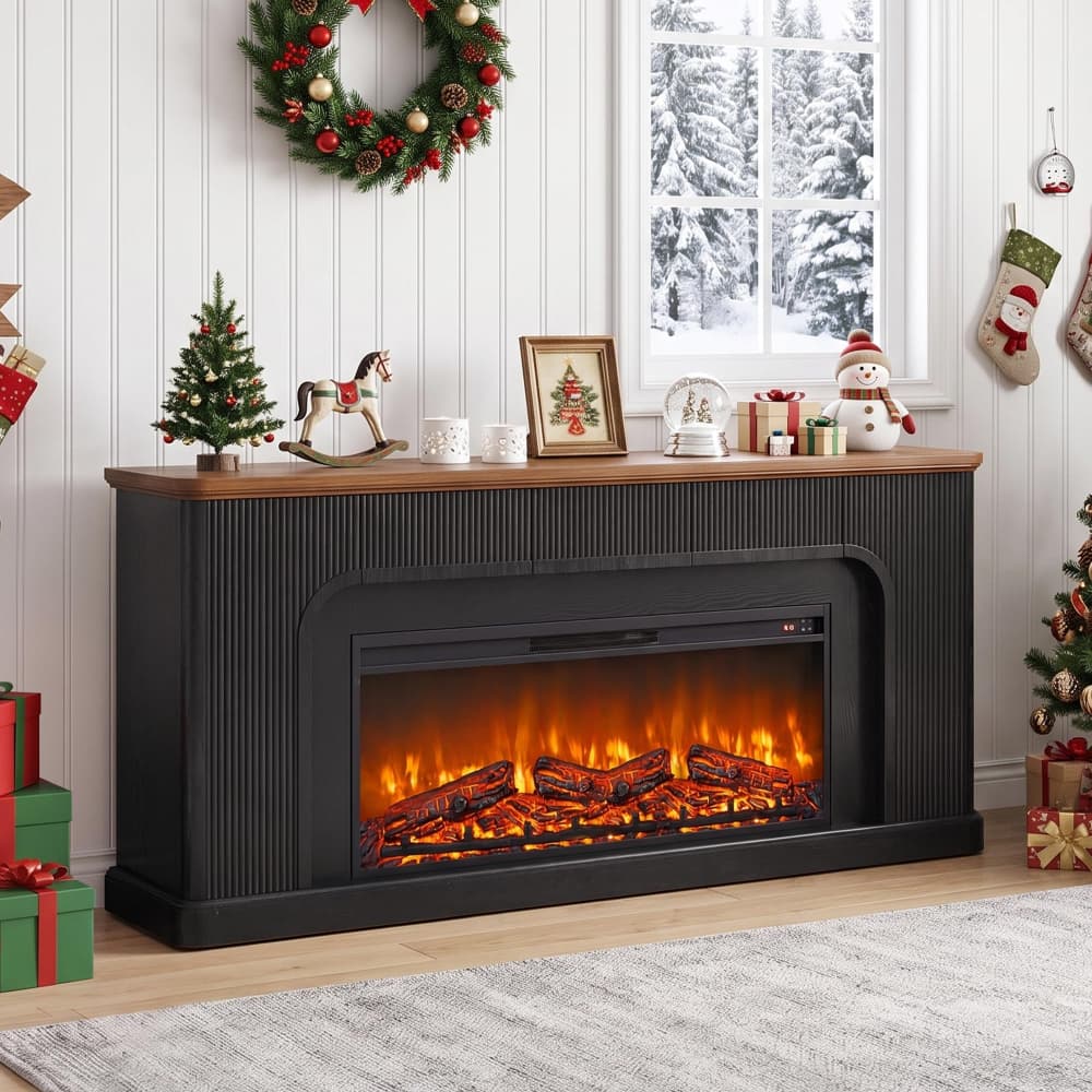 A black electric fireplace with a faux wood log fire burning inside, set against a white paneled wall in a decorated living room with Christmas wreaths, gifts, and holiday decor.