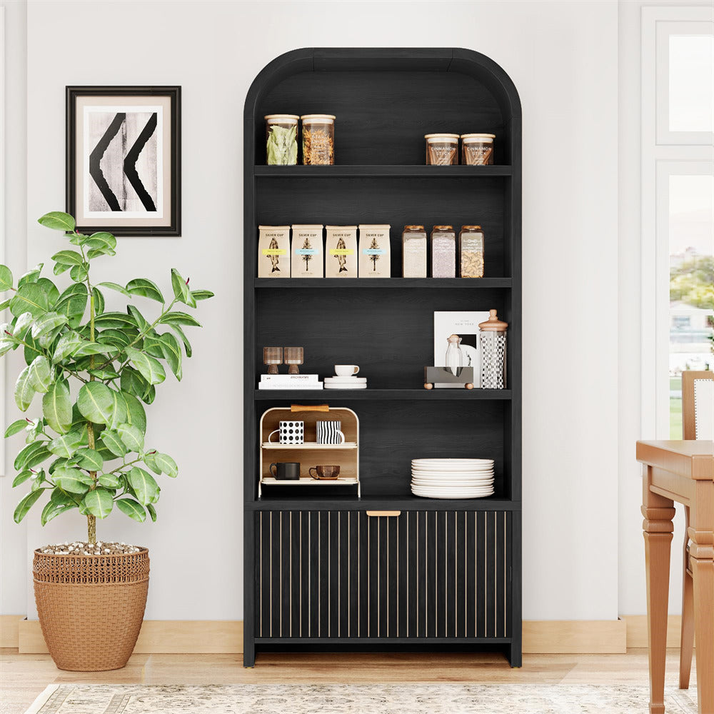 Black bookshelf with decorative items in a room with a plant and table.