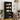 Black bookshelf with kitchen appliances in a room with a dining table and chairs.