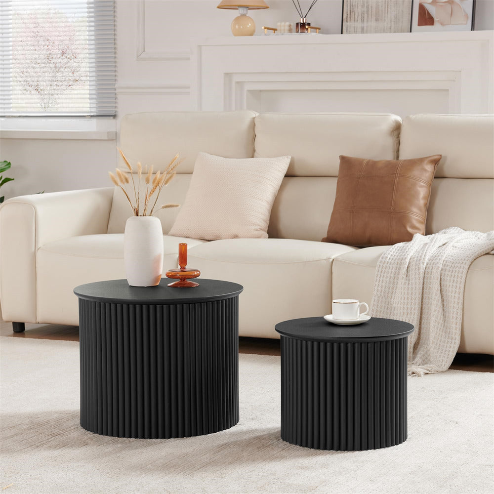 Two black side tables in front of a beige sofa with decorative items.