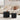 Two black side tables in front of a beige sofa with decorative items.