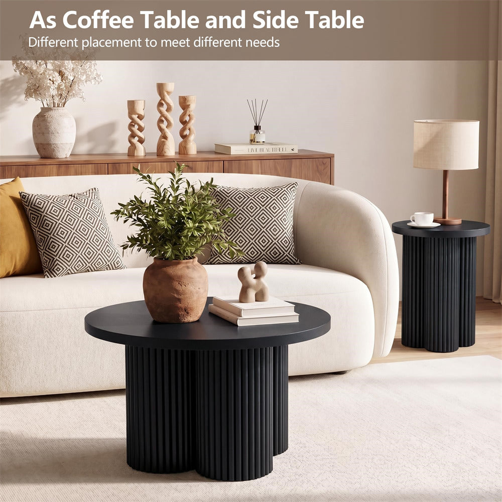 A modern living room scene showing two black fluted side tables: a round coffee table in the foreground and a taller side table to the right. The setting includes a cream sofa, patterned pillows, a lamp, and decor, with overlaid text at the top reading 'As Coffee Table and Side Table Different placement to meet different needs.