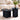 Two modern nesting side tables in matte black with fluted pedestal bases, styled in a bright living room with a cream sofa, a glass of whiskey, books, and a potted plant.