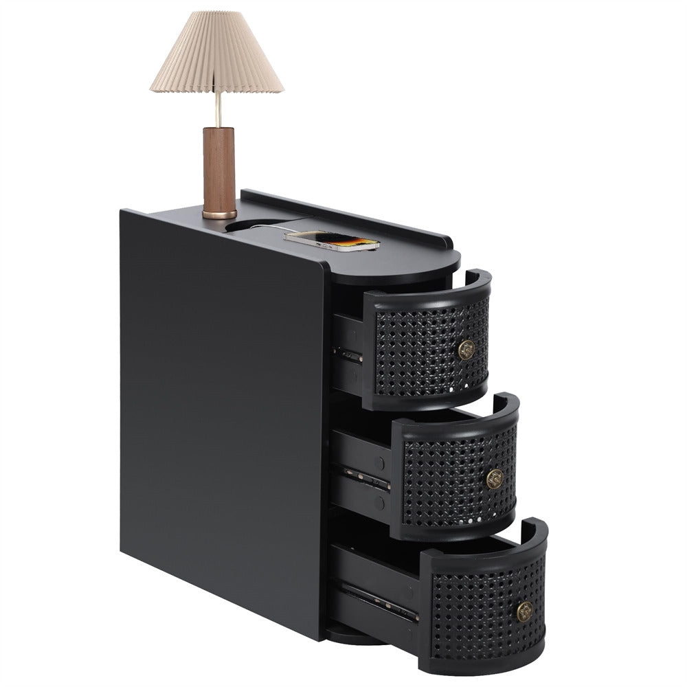 Black nightstand with three drawers and a small lamp on a white background