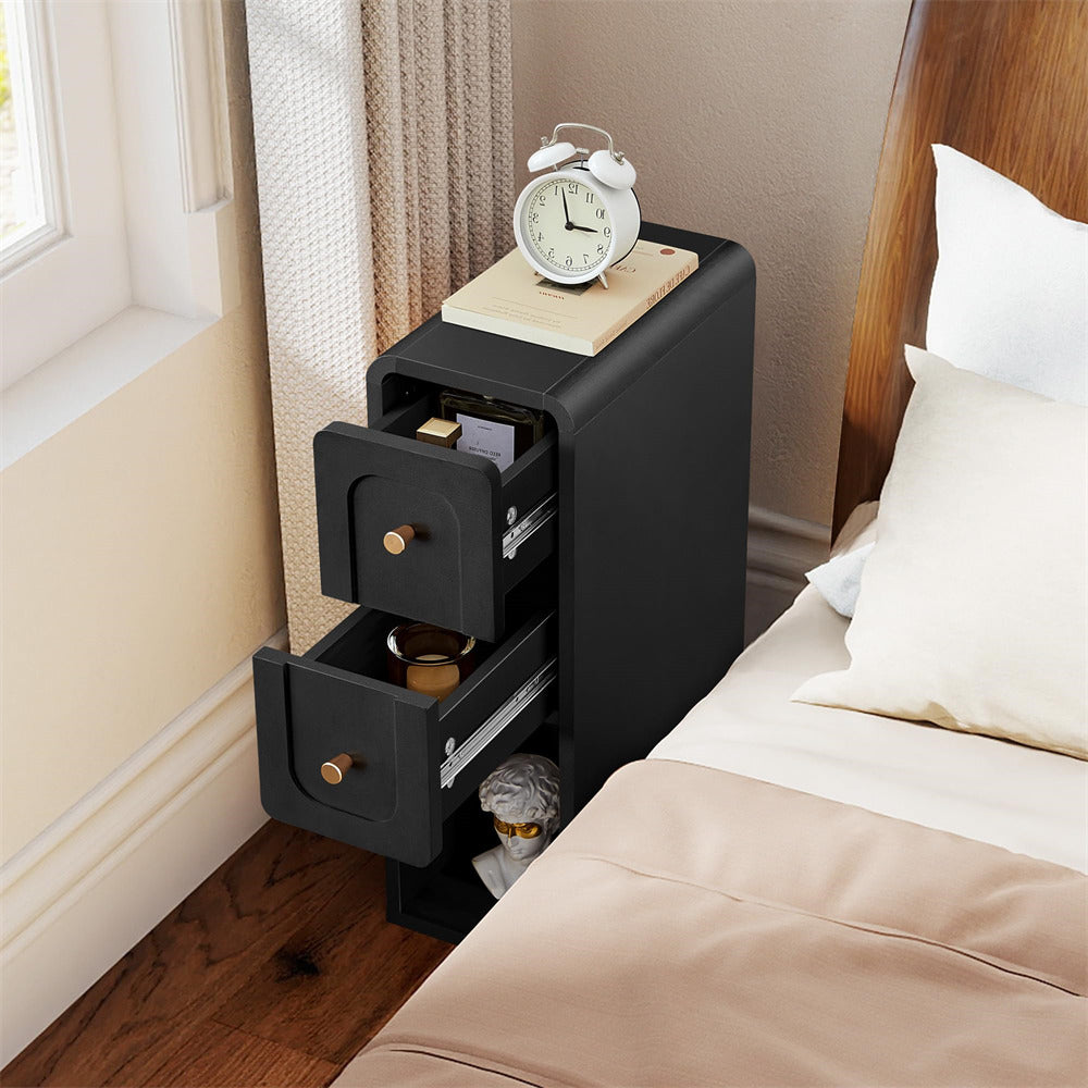 Black nightstand with open drawer next to a bed in a bedroom.