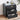 Black three-drawer nightstand with decorative items on a wooden floor.