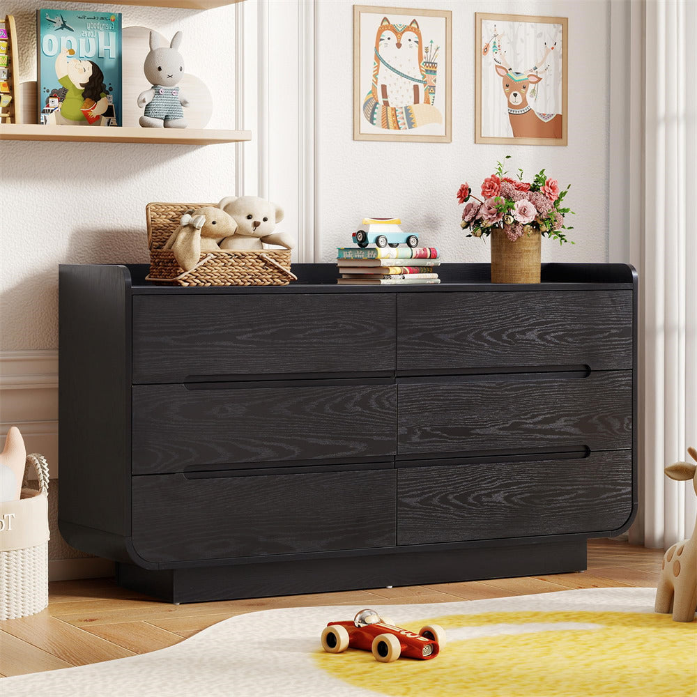 Black 6-drawer dresser in a room with toys, books, and decor items on top