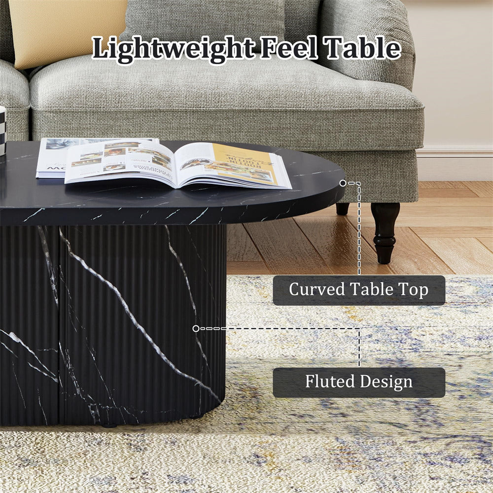 Black marble coffee table with curved top and fluted design in a living room setting.