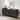Black sideboard with geometric pattern in a room with a white brick wall and framed artwork.