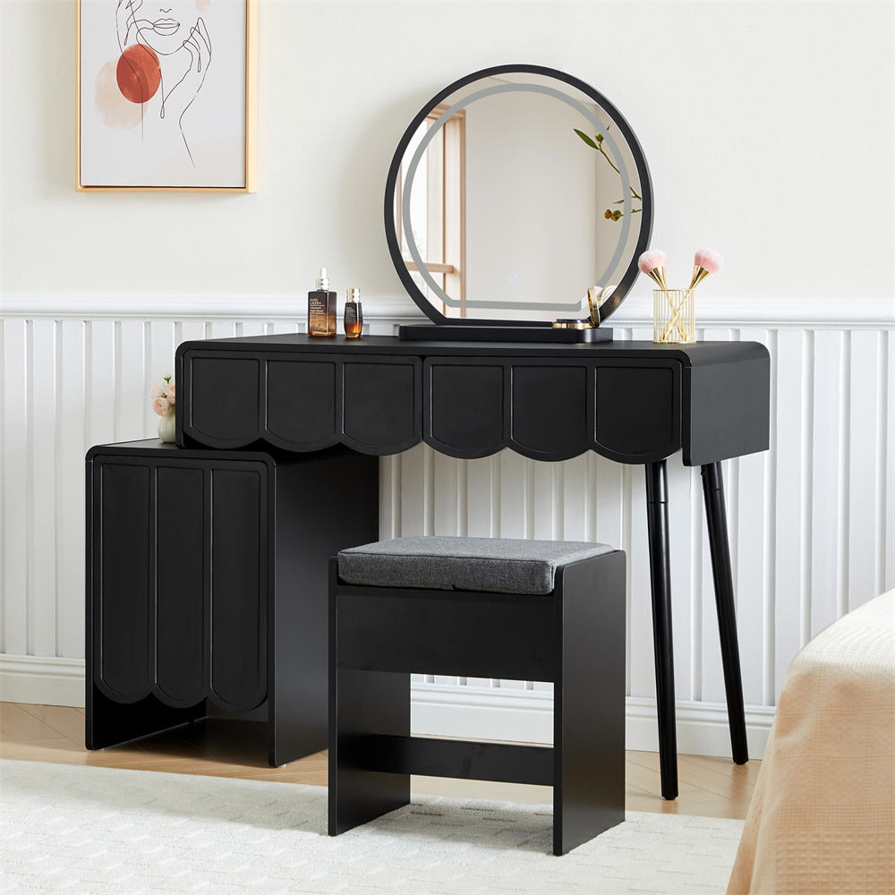 Black vanity table with round mirror and stool in a room setting.