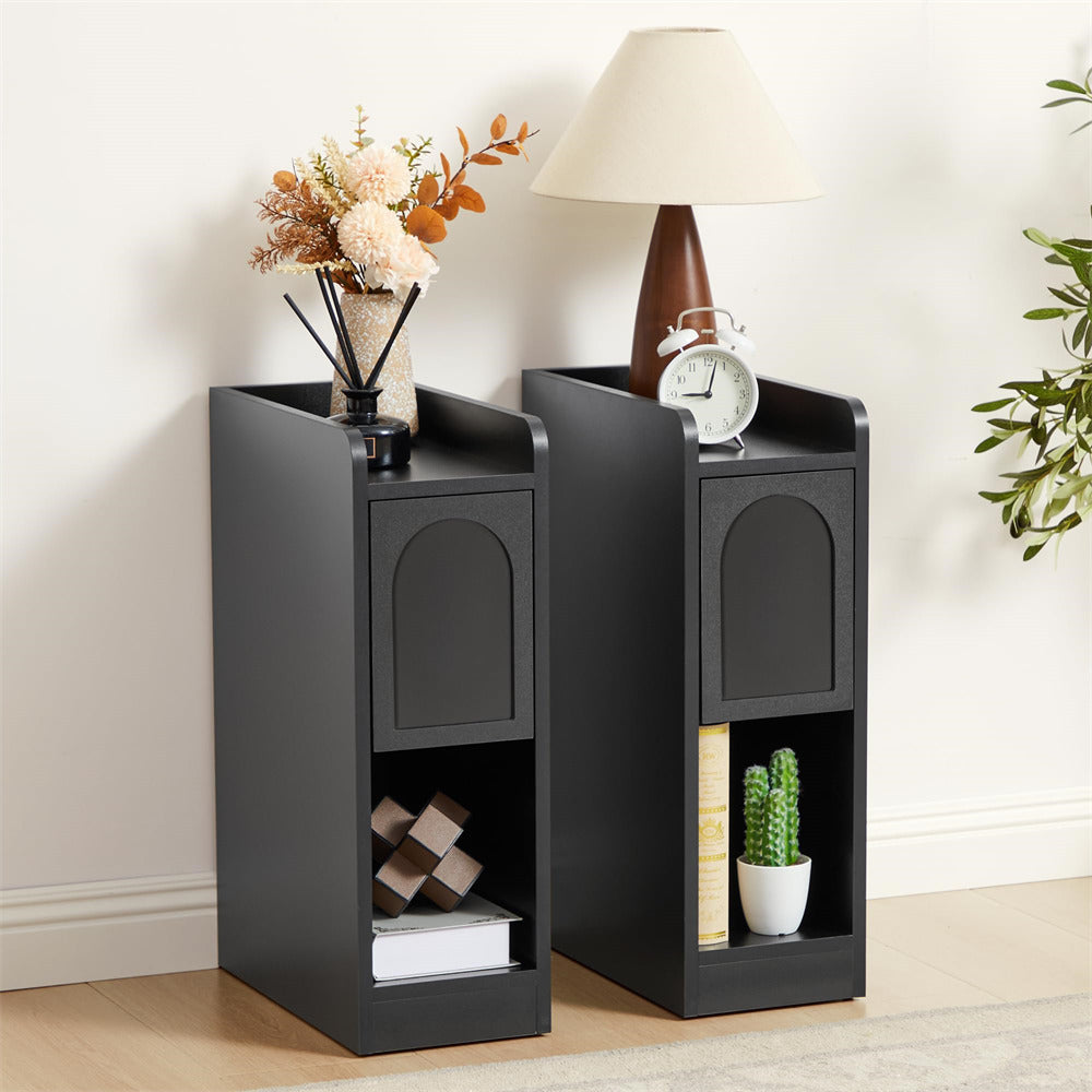 Two black side tables with decorative items on a light wood floor.