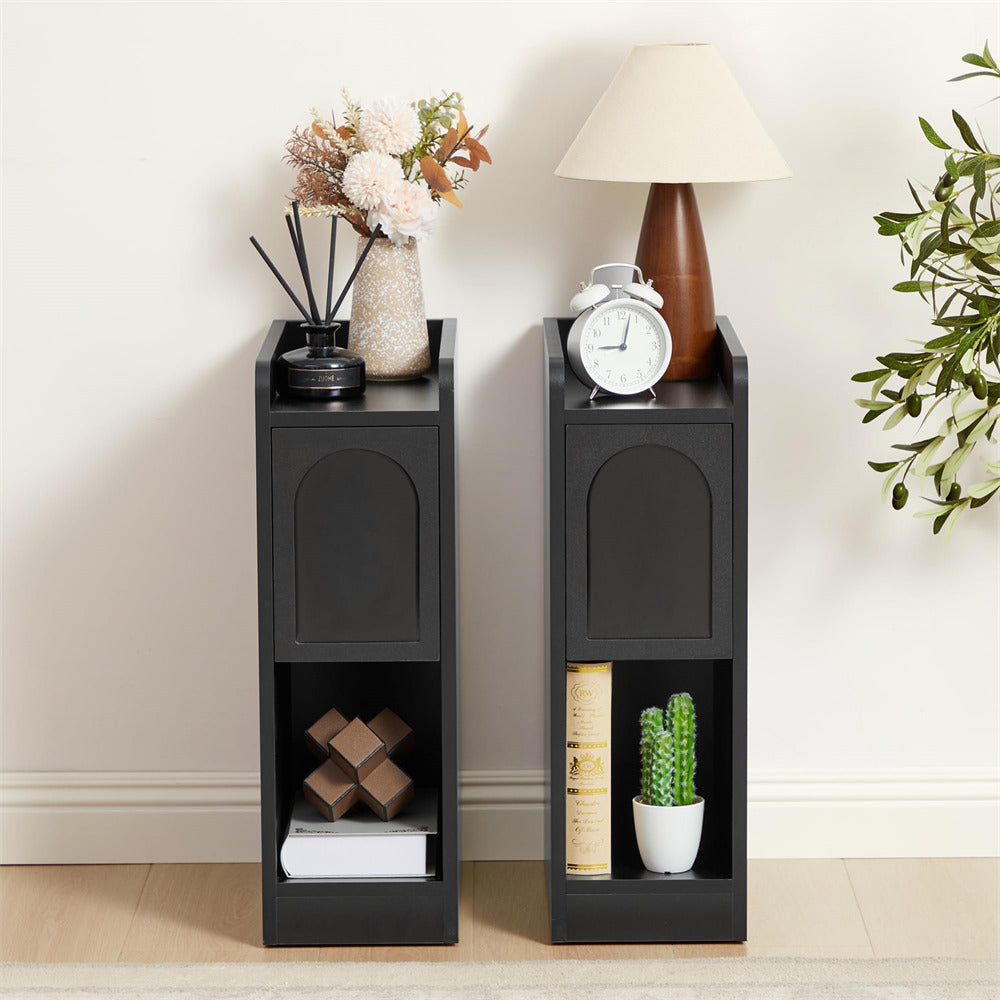Two black side tables with decorative items against a white wall.